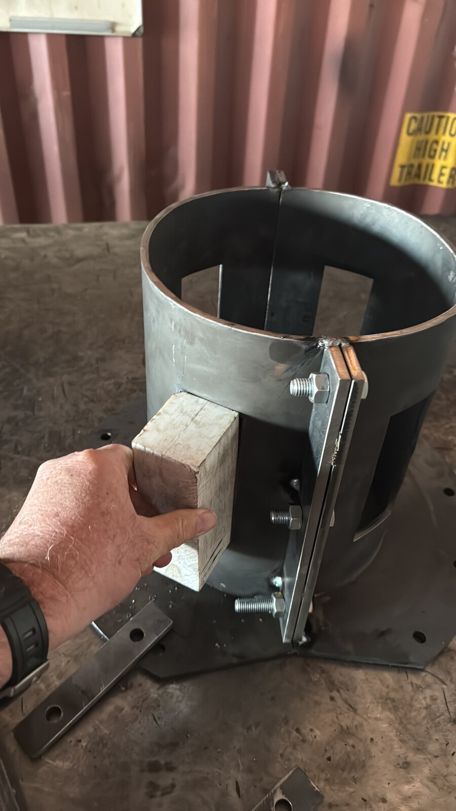 The bare-steel drill bush on its base plate with a white Ertalyte guide block being fitted and adjustment studs visible, a hand for scale