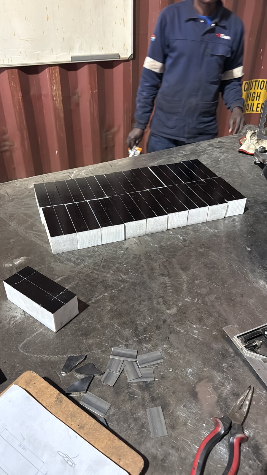 Ertalyte guide blocks cut and prepped on the workshop bench alongside small steel parts