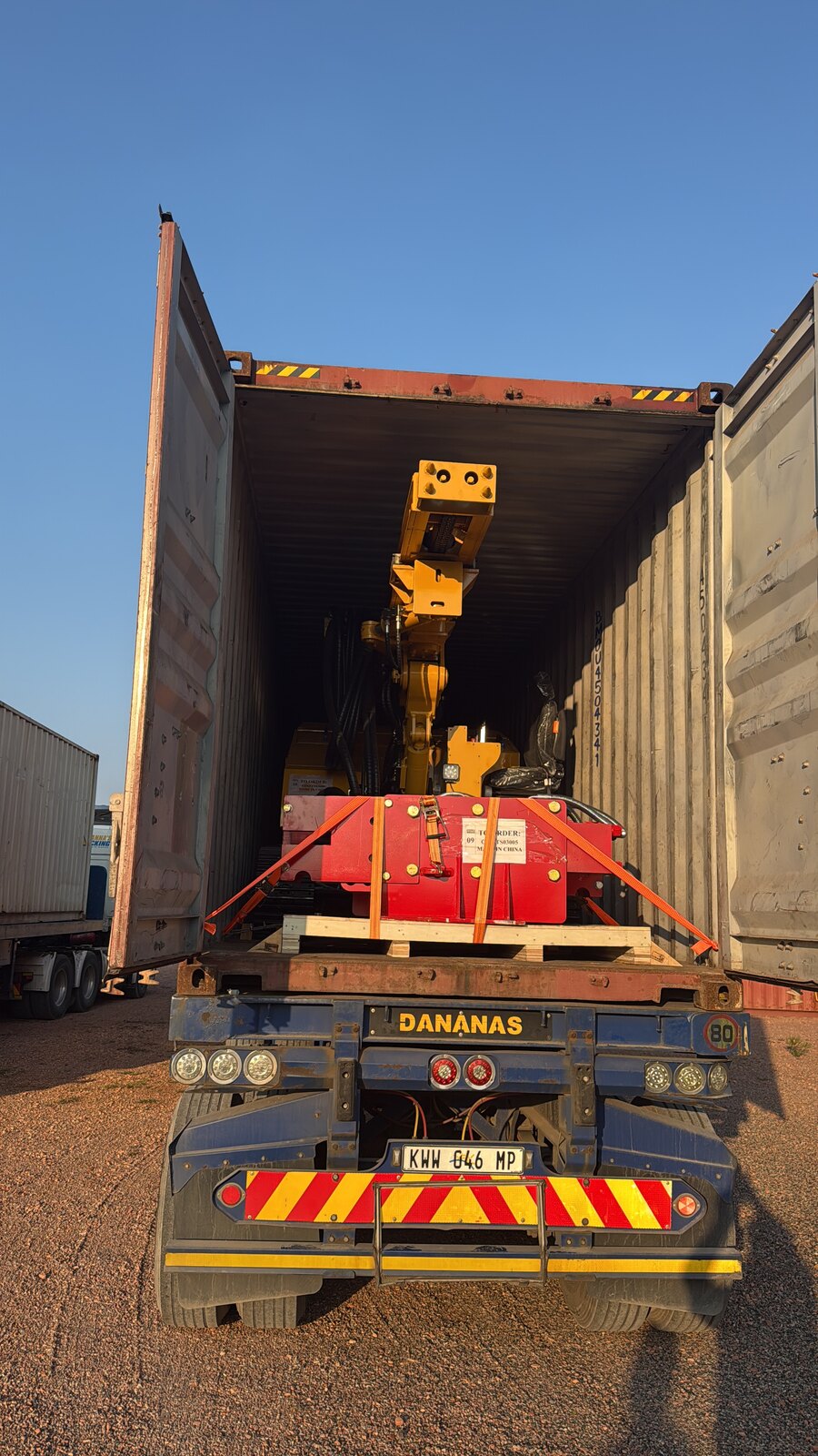Solar piling rig with red base lashed down inside a shipping container, in as-shipped condition