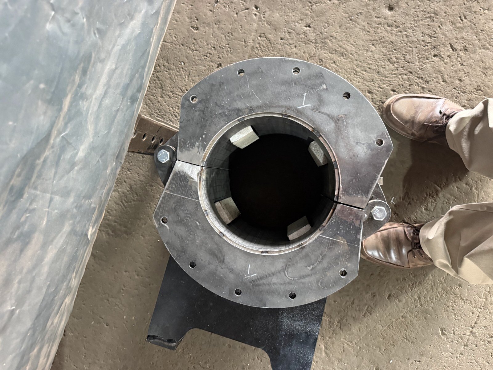 Looking straight down into the drill bush at four Ertalyte guide pads spaced around the bore that centre the hammer, with the split seam and hinge bolt across the flange