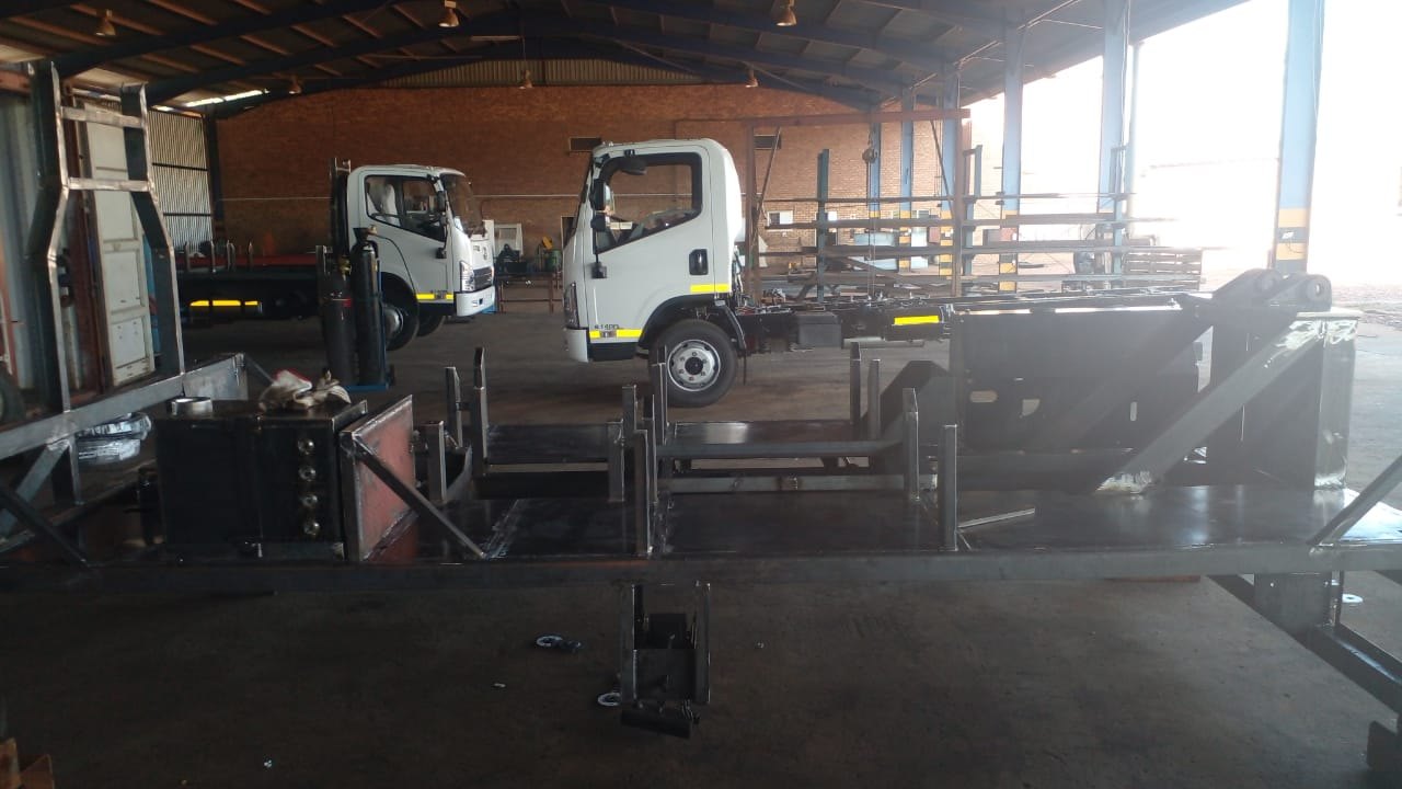 Bare cab-chassis trucks and freshly welded loadbody frames standing in the Drillbuilders workshop in Mokopane, waiting for rig fitment