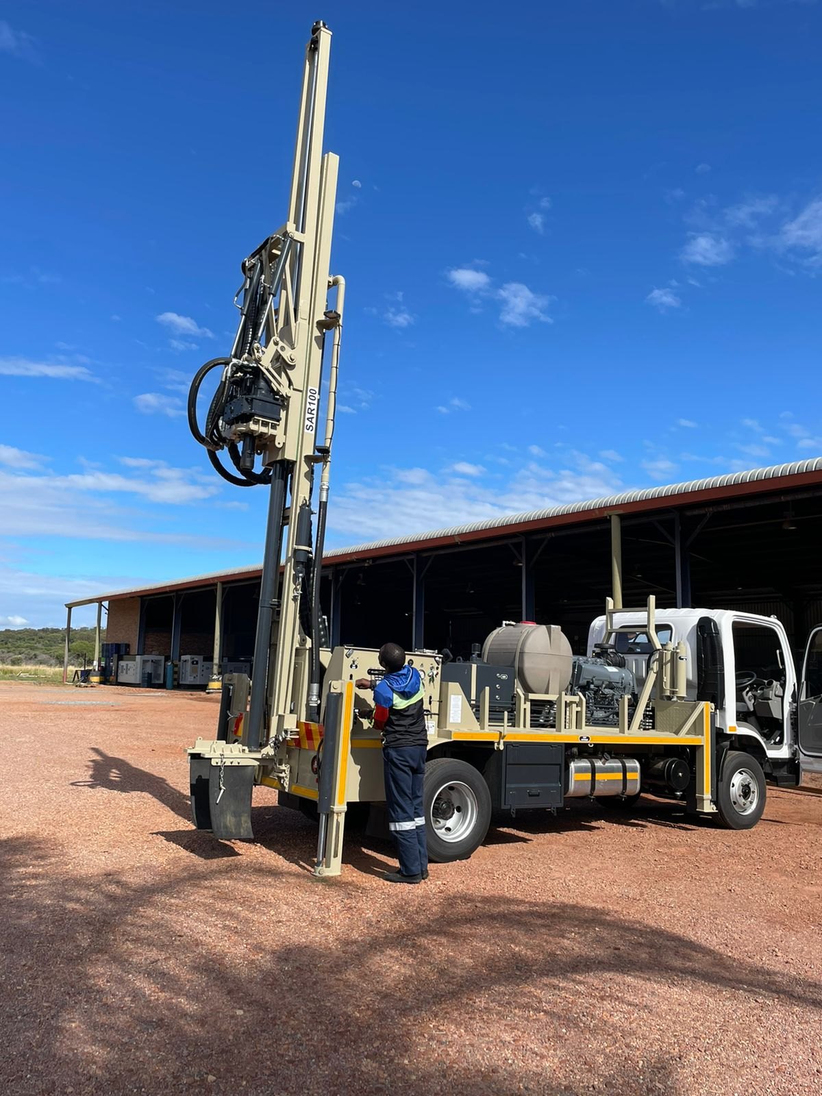 Handover training at the Drillbuilders factory: an operator on the controls of a new desert-tan SAR100 with the mast raised