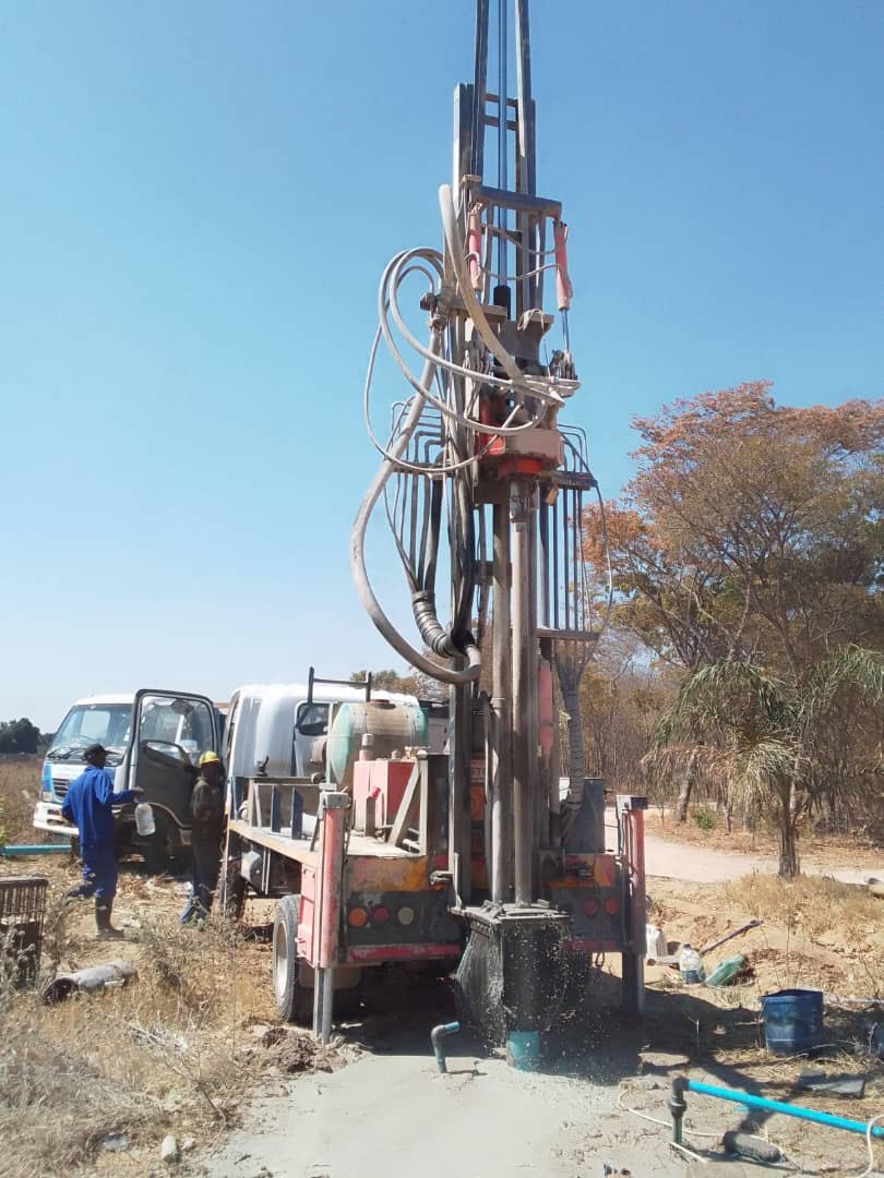 Truck-mounted drilling rig on site with water flowing from the borehole